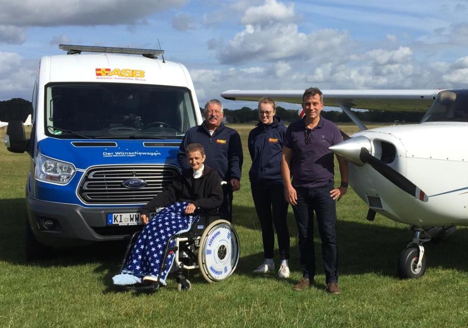 Der Wünschewagen neben dem Flugzeug zusammen mit Gast Gabriela, Wunscherfüllern Helmut Holstein und Helena-Zoe Klein und dem Piloten