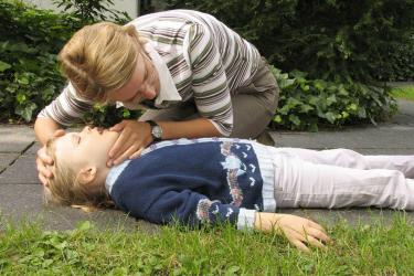Frau leistet erste Hilfe an Kind