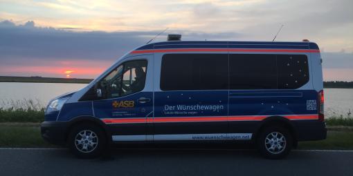 Der Wünschewagen vor einem Sonnenuntergang.